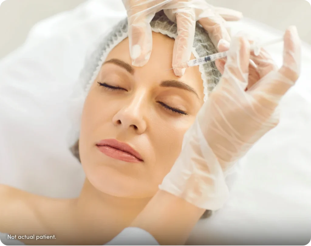 Woman wearing a hair cap being injected by gloved hands