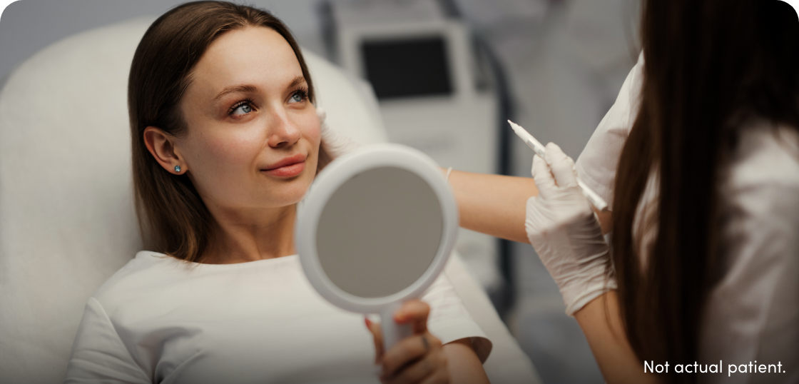 Woman holding mirror speaking with her injector.