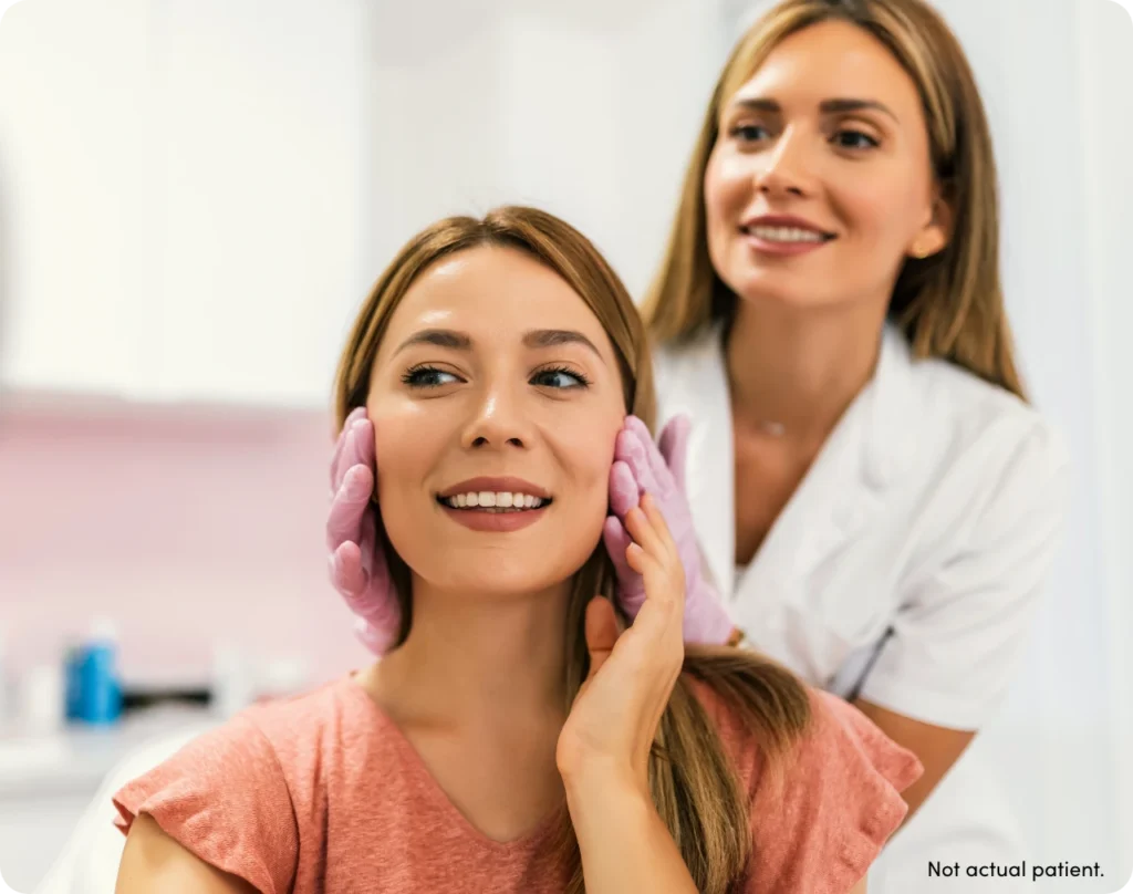 Doctor and patient smiling and consulting while looking at patient's face with text 'not actual patient'.