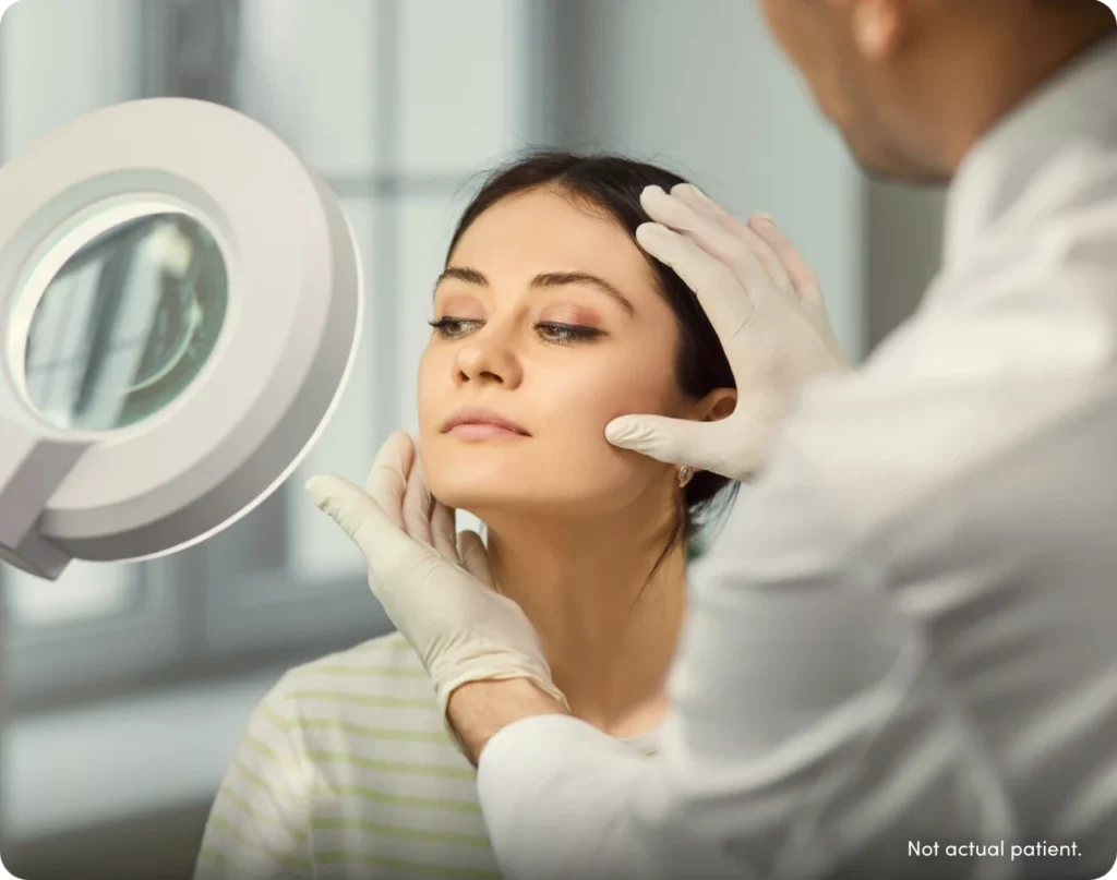 Woman with light on her face consulting with injector. With text 'not actual patient'